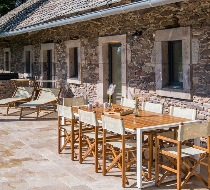 Vue de la terrasse avec table de jardin du gîte de la Porcherie avec piscine, location de gîte au bord du lac de Pareloup en Aveyron avec accès direct au lac